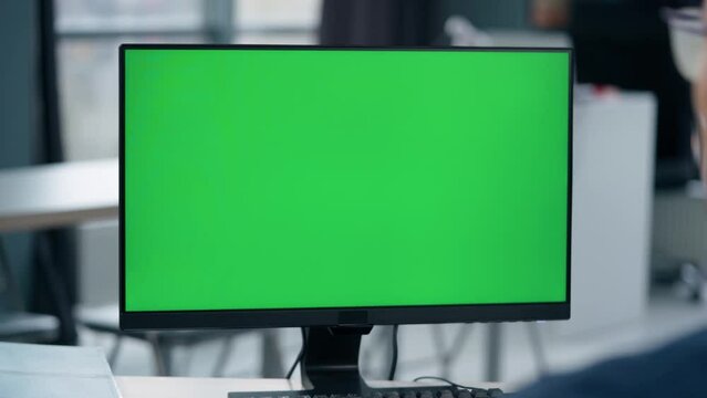 oung Man Working At Computer With Green Mock Up Screen in Office. Close Up Desktop Computer Monitor with Mock Up Green Screen Chroma Key Display