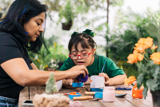 Mother and daughter painting a potted plant in the garden.