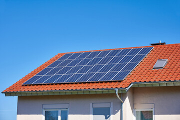 Solarzellen auf rotem Hausdach vor blauem Himmel