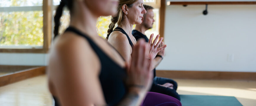 Meditative group yoga class practice inside modern studio.
