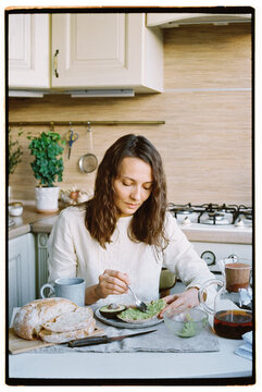 Woman eating breakfast at home in the kitchen.