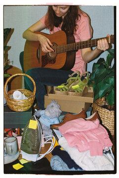 A female vendor plays the guitar at a flea market.