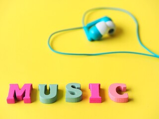 Concept of loving music blue wired earphones heart shaped and the word music on a yellow background