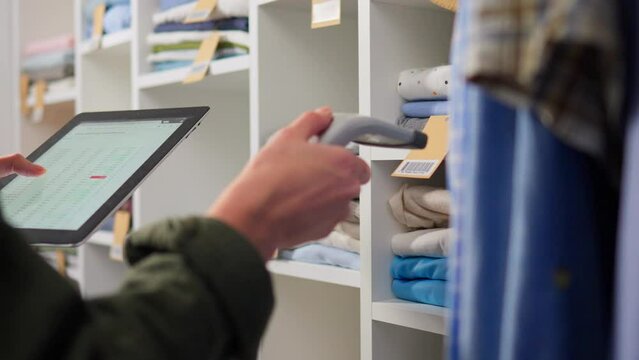 Clothes on a hanger, Stylish woman Carefully Scans a barcode with a scanner. Wooden hangers for clothes, Close-up Sales assistant Going through hangers with clothes in a warehouse, business woman
