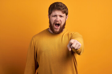 Furious angry unshaven man looses temper, going crazy, screams with irritation and points at you,...