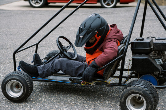 boy riding a go kart outdoors by himself in an abandoned parking lot