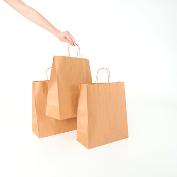 Craft bags with human hand on a white background. Place for text and logo. The concept of packaging, packaging, eco-packaging of products, food, own style and brand. High quality photo