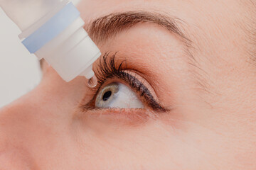 Crop woman instilling eye drops