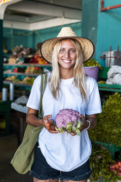 Woman buying pink cauliflower in market