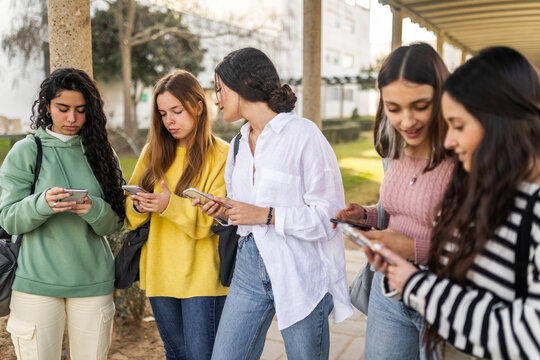 female student friends using mobile phone in university campus