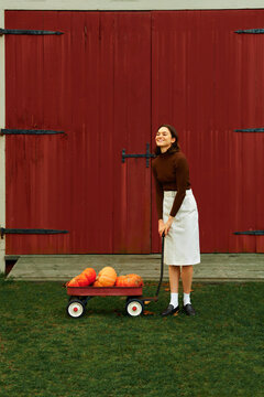 Smiling Woman pulling a pumpkin cart 