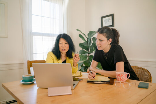 two women looking at laptop & working  together on project 
