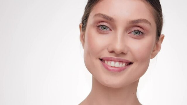 Portrait young smiling beautiful woman with natural makeup look at the camera. Cosmetology. Close up portrait Adorable half-naked female in studio. Advertising fresh clean healthy skin care concept.