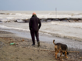 A man with his dog for a walk by the water