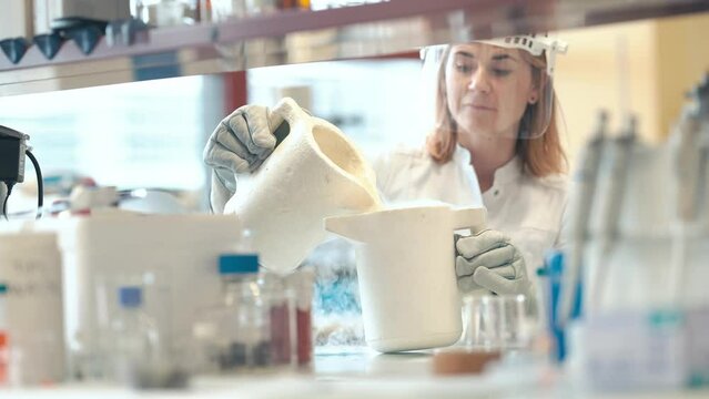 research with liquid nitrogen in the laboratory is carried out by a young female scientist with a protective glass face mask