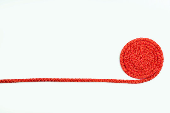 A red rope twisted around lies on a white isolated background. Free space for text. Red nylon rope twisted around. Red thread on a white background with a top view