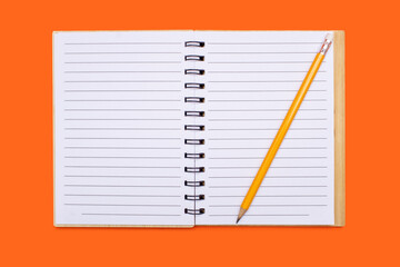 An open notebook with a binder and a yellow pencil on an orange background. Open notepad with blank sheets in top view. Free space for text. Blank notebook pages ready to be used in design