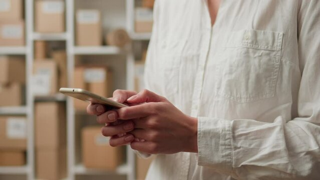 Productivity, Woman business man In the process holding a smartphone in the e-commerce room, Close-up Product packer is in the industrial workshop of the actual business, workplace
