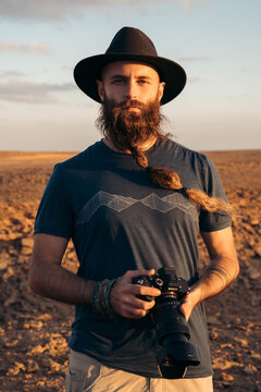 Traveler with beard holding a camera in the desert