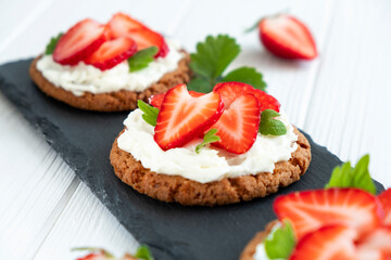 Strawberry tart with oat biscuit and whipped cream on black slate board. Recipe of simple berry cake for breakfast or holiday. Summer light dessert.