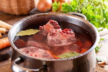 Raw veal beef Oxtail Meat with carrots, onions and spices in a saucepan on the table. Bone Broth Bouillon preparation