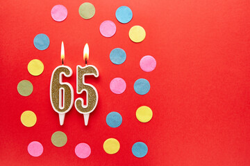Number 65 on a red background with colored confetti. Happy birthday candles. The concept of...
