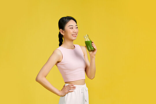 Portrait of young smiling millenial woman drinking green smoothie