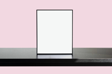 Poster Frame Mockup on black wooden table with Pastel Pink color wall