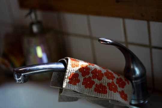 Kitchen faucet with a red flowered rag and natural light