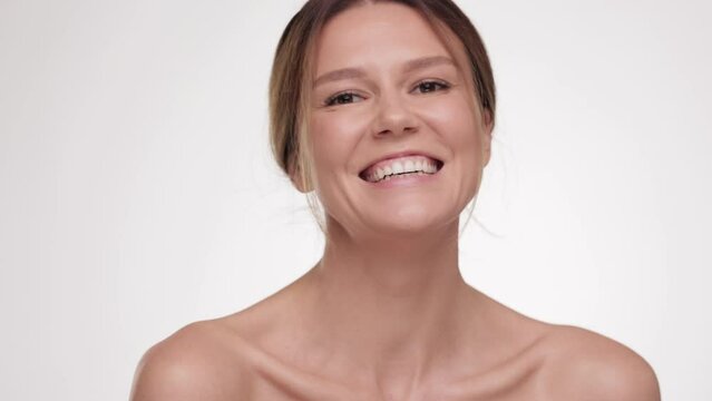 Happy half-naked brunette female in studio. Beautiful woman with natural makeup look at the camera. Cosmetology. Close up portrait Advertising fresh clean healthy skin care concept.