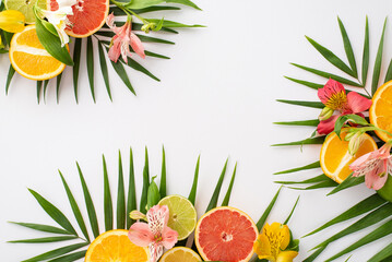 A refreshing summer treat. Top view flat lay of alstroemeria blooms with citrus slices and palm leaves on a white background with an empty space for text or ad