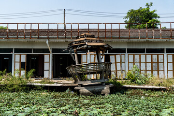A broken old wooden gazebo in front of water lilies in Thailand