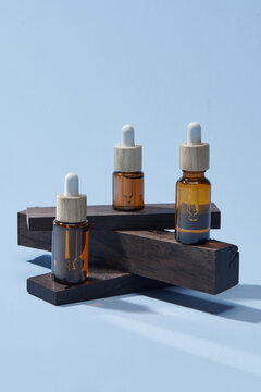 Bottle with pipette standing on podium made from dark wooden