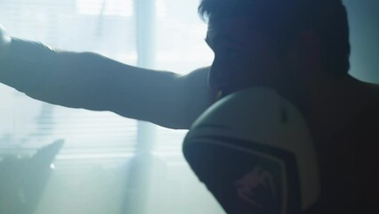 Caucasian muscular man practicing punches for boxing training. The guy is aggressively boxing, hitting the hands of the trainer in the hall. Active sports and martial arts. High quality 4k footage