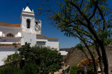 TAVIRA, PORTUGAL - JUNE 28, 2022: Bell tower and clock tower of the Santa Maria do Castelo church...