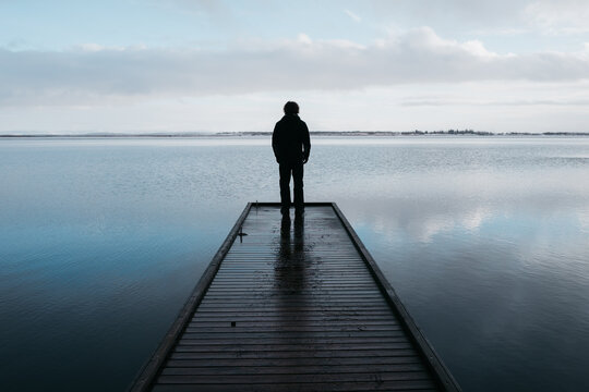 Young man looks out over cold lake in Iceland