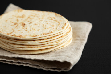 Stack of Whole Wheat Flour Tortillas on a black background, side view. Close-up.