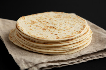 Stack of Whole Wheat Flour Tortillas on a black background, side view. Close-up.