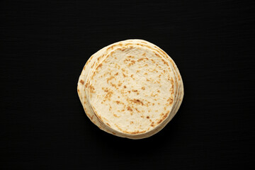 Stack of Whole Wheat Flour Tortillas on a black background, top view. Flat lay, overhead, from above.