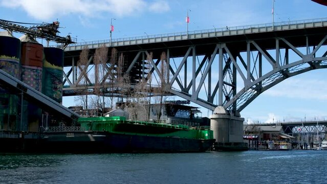 Bridge to greenville and water bus passing under the bridge Nature Canada Vancouver Pacific Ocean Pier and pillars on the pier Granville Island aquabus Skyscrapers in the background 2023 Canada