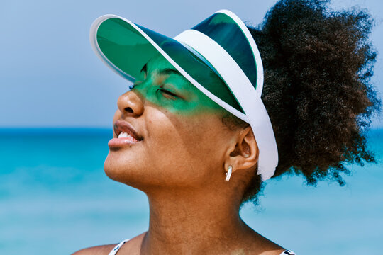 black woman in visor hat against sky