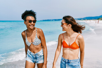 Obraz premium Happy diverse friends walking on beach