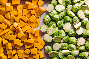 Pumpkin cubes and brussel sprouts halves on the tray, prepared to bake