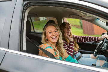 Excited girl friends traveling by car 