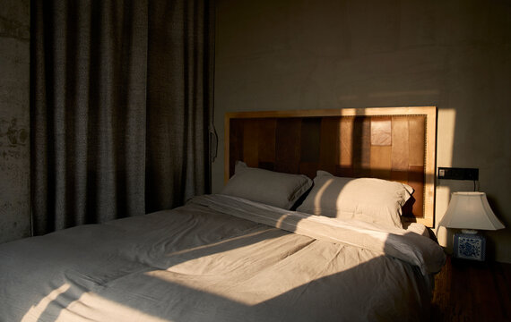 Comfortable big bed in bedroom with morning sun shining in