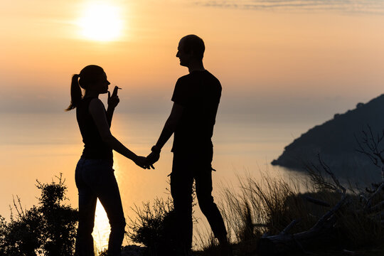 Silhouettes of couple on the rock above the sea