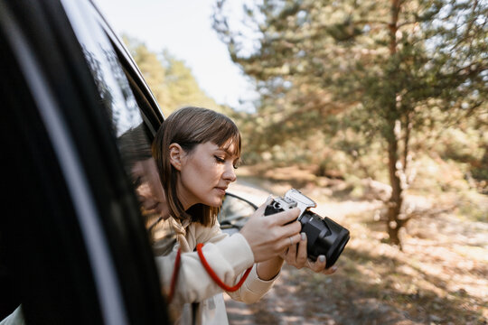 Woman taking a picture looking out of a car window