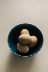 On a plain background there is a blue bowl with eggs dyed with natural dye for the Easter holiday. Minimalism.