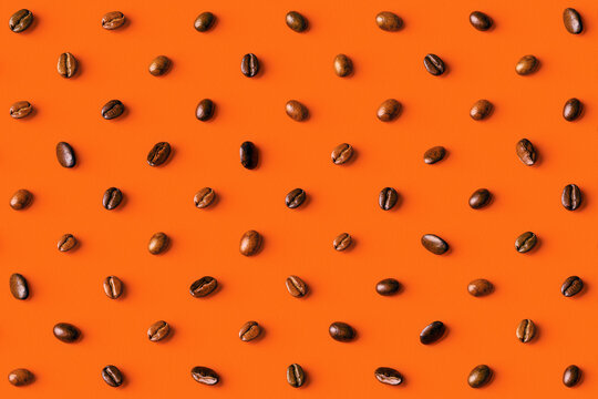 Overhead view of coffee beans on orange background