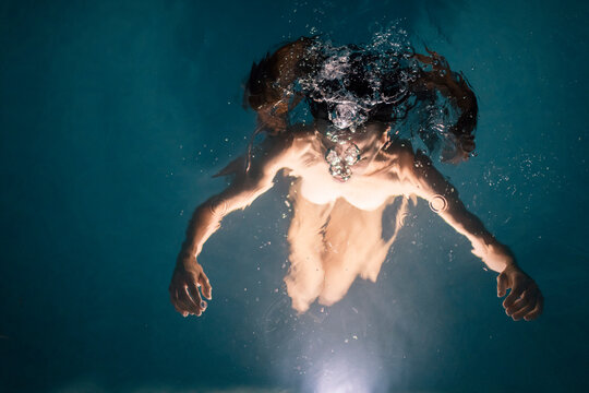 Anonymous woman inside illuminated swimming pool